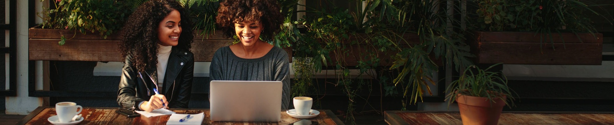 Women with laptop in front of plant wall